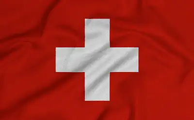 Eine grafische Darstellung der Nationalflagge der Schweiz, die ein weißes, aufrechtes, freistehendes Kreuz auf rotem Grund zeigt. Die Flagge ist mit einem realistischen Faltenwurf und dezenten Schattierungen gestaltet, die den Eindruck eines wehenden oder leicht zerknitterten Stoffes vermitteln. Die Farben sind kräftig und flächig ohne zusätzliche Symbole oder Beschriftungen.