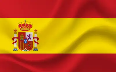 Eine grafische Darstellung der Nationalflagge Spaniens mit den horizontalen Streifen in Rot, Gelb und Rot, wobei der gelbe Mittelstreifen doppelt so breit ist wie die roten Randstreifen. Im linken Drittel des gelben Streifens ist das spanische Staatswappen abgebildet. Die Flagge ist mit einem realistischen Faltenwurf und Schattierungen gestaltet, die den Eindruck eines wehenden Stoffes im Wind vermitteln. Die Farben sind kräftig und flächig gestaltet.